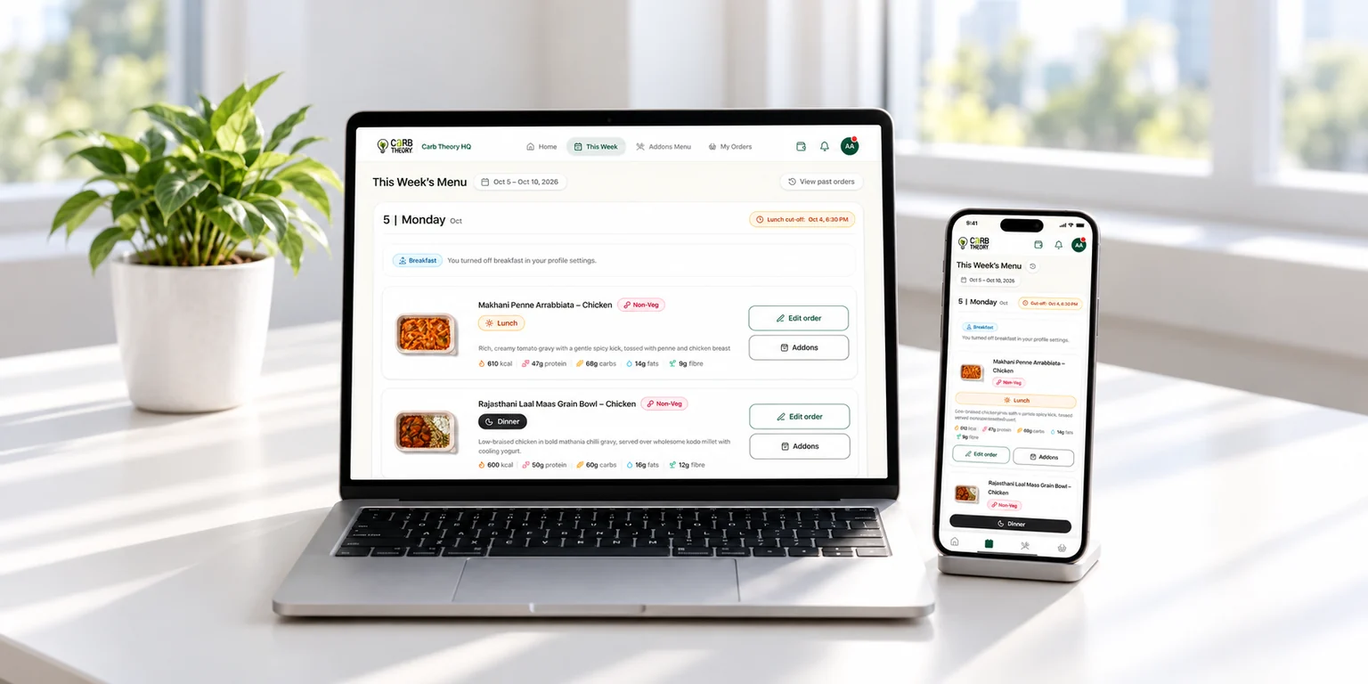 Carb Theory employee meal app showcased on a laptop and smartphone on a bright white office desk with a tabletop plant