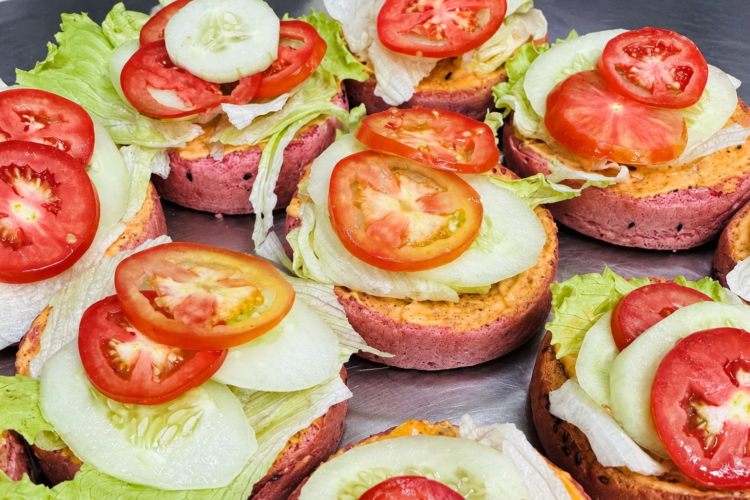 Open pink beetroot burger buns layered with lettuce, cucumber and tomato in the Carb Theory kitchen