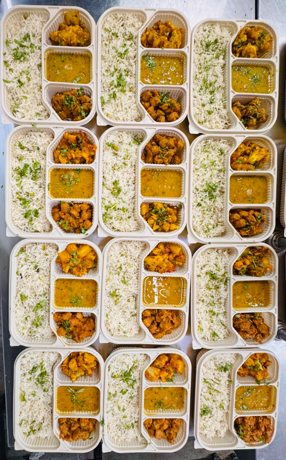 Freshly prepared meal prep containers arranged in rows, featuring herb rice, dal, roasted vegetables, and paneer curry at Carb Theory in Bangalore.